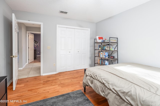 bedroom with a textured ceiling, light hardwood / wood-style flooring, and a closet