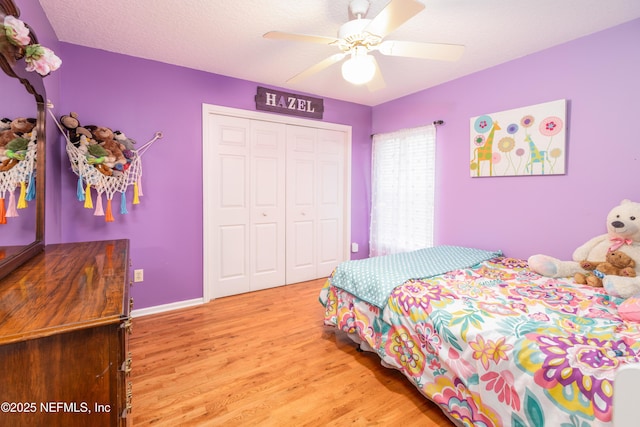 bedroom with ceiling fan, a closet, light hardwood / wood-style floors, and a textured ceiling