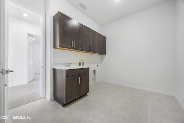 clothes washing area featuring sink, cabinets, electric dryer hookup, hookup for a washing machine, and light tile patterned flooring