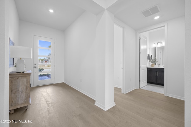 corridor with sink and light hardwood / wood-style flooring