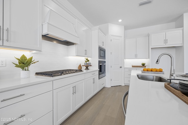 kitchen featuring premium range hood, white cabinets, and appliances with stainless steel finishes