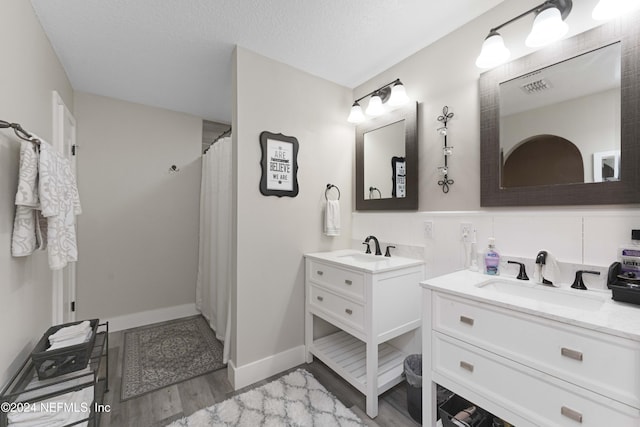 bathroom with vanity, wood-type flooring, a textured ceiling, and walk in shower