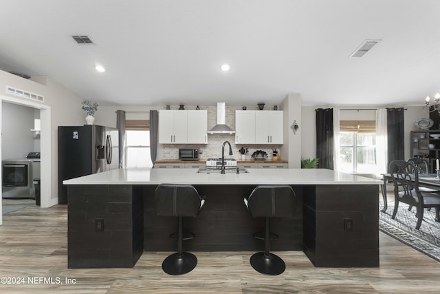 kitchen featuring a spacious island, washer / dryer, wall chimney range hood, and white cabinets