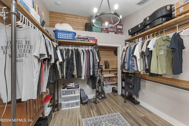 spacious closet with an inviting chandelier and hardwood / wood-style flooring