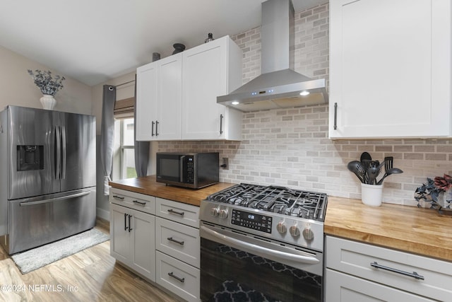 kitchen with backsplash, wood counters, wall chimney exhaust hood, and appliances with stainless steel finishes