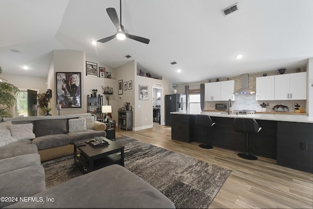 living room with plenty of natural light, ceiling fan, light hardwood / wood-style flooring, and vaulted ceiling