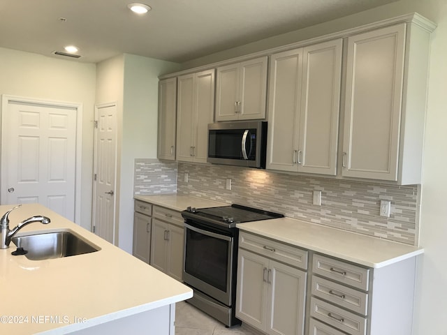 kitchen with appliances with stainless steel finishes, tasteful backsplash, sink, gray cabinets, and light tile patterned flooring