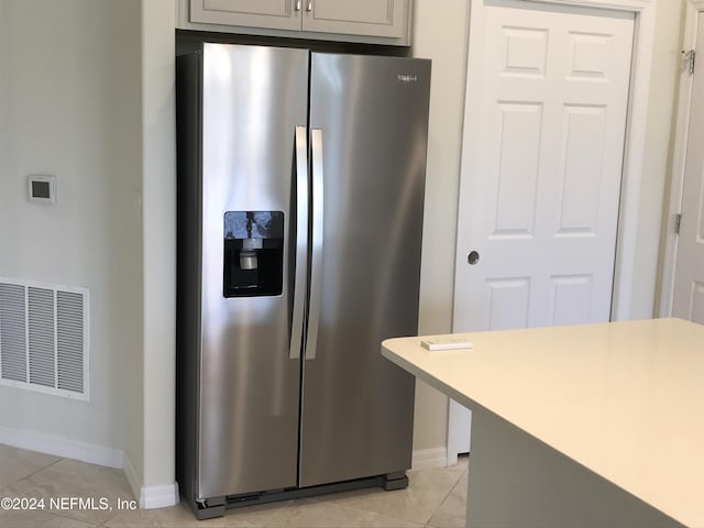 kitchen featuring stainless steel fridge with ice dispenser, light tile patterned floors, and gray cabinetry