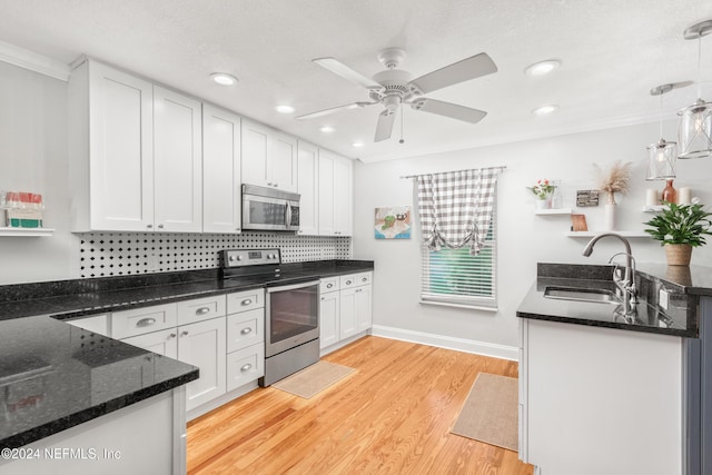 kitchen featuring hanging light fixtures, white cabinets, stainless steel appliances, and sink