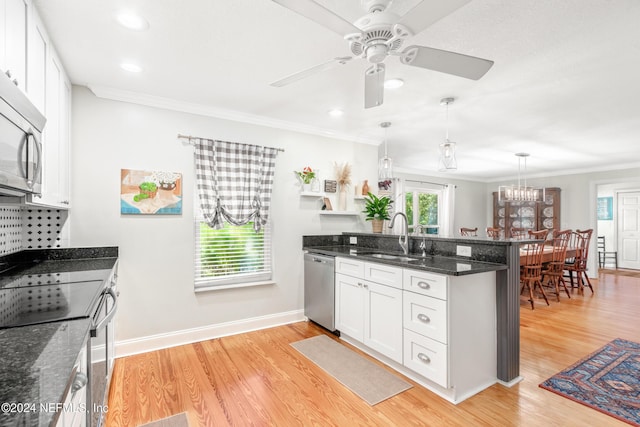 kitchen with hanging light fixtures, sink, white cabinets, and stainless steel appliances