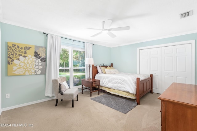 bedroom with crown molding, ceiling fan, a closet, and light colored carpet