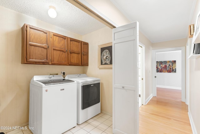 clothes washing area featuring cabinets, independent washer and dryer, a textured ceiling, and light tile patterned floors