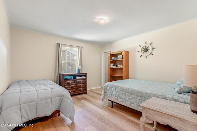 bedroom with ornamental molding and light hardwood / wood-style flooring