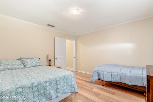 bedroom featuring crown molding and light hardwood / wood-style floors