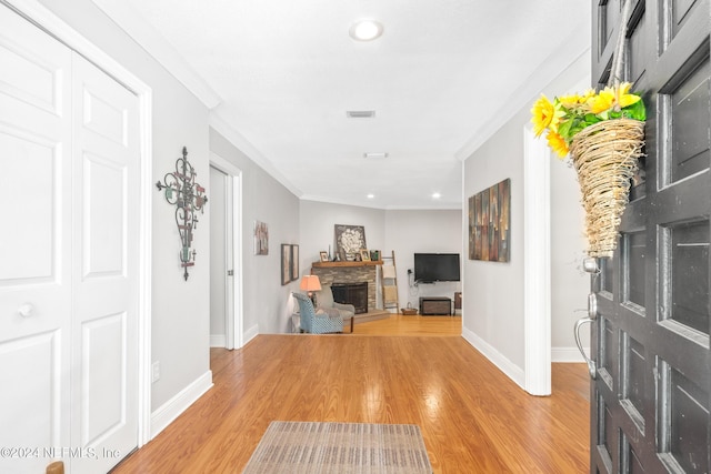 entrance foyer featuring a fireplace, light hardwood / wood-style floors, and ornamental molding