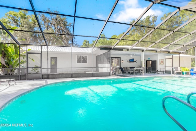 view of pool with glass enclosure and a patio