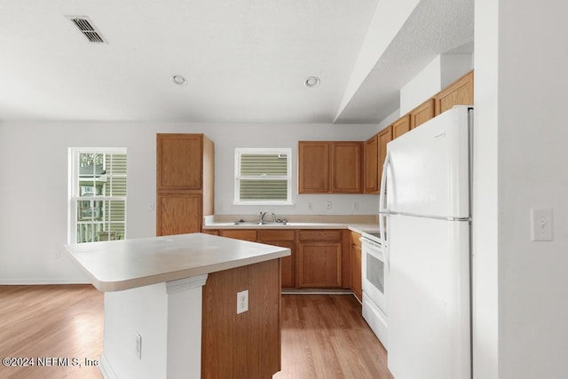 kitchen featuring light hardwood / wood-style flooring, a kitchen island, white appliances, and sink