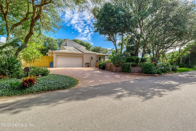 view of front facade featuring a garage, decorative driveway, and fence