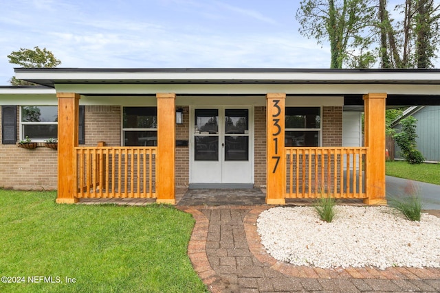 view of exterior entry with a porch and a lawn