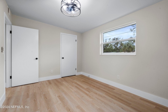 unfurnished bedroom featuring lofted ceiling and light hardwood / wood-style flooring