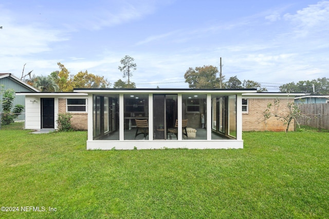 back of property with a sunroom and a yard