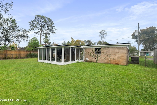 back of house with a lawn, a sunroom, and central air condition unit