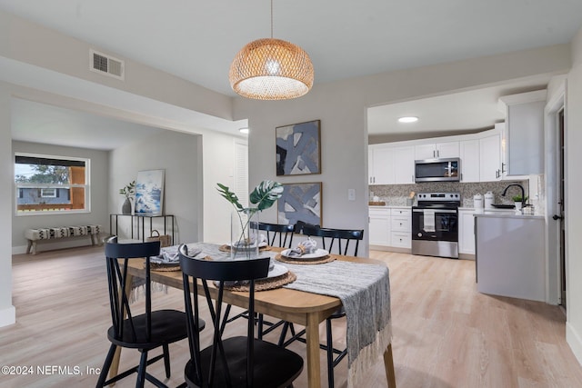 dining area featuring light wood-type flooring and sink