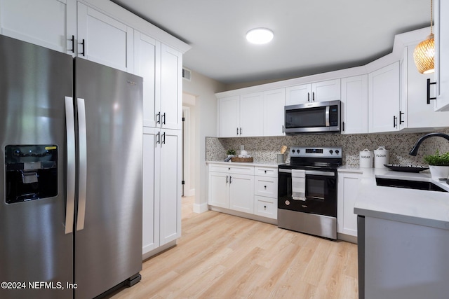 kitchen featuring decorative light fixtures, white cabinetry, sink, and appliances with stainless steel finishes