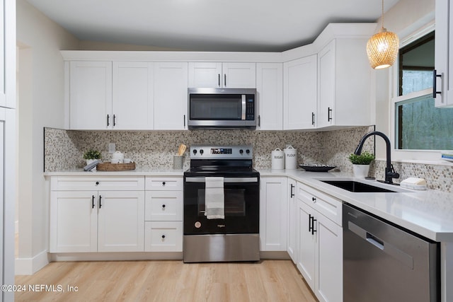 kitchen featuring sink, stainless steel appliances, backsplash, decorative light fixtures, and white cabinets