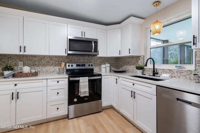 kitchen with hanging light fixtures, white cabinetry, sink, and stainless steel appliances