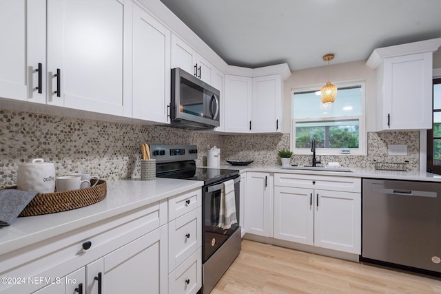 kitchen featuring decorative backsplash, appliances with stainless steel finishes, sink, pendant lighting, and white cabinetry