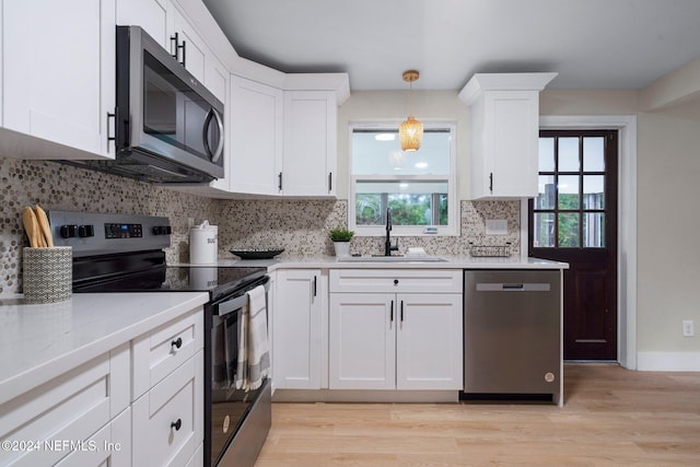 kitchen featuring white cabinetry, sink, stainless steel appliances, backsplash, and decorative light fixtures