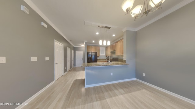 kitchen featuring kitchen peninsula, light brown cabinetry, black refrigerator with ice dispenser, and hanging light fixtures