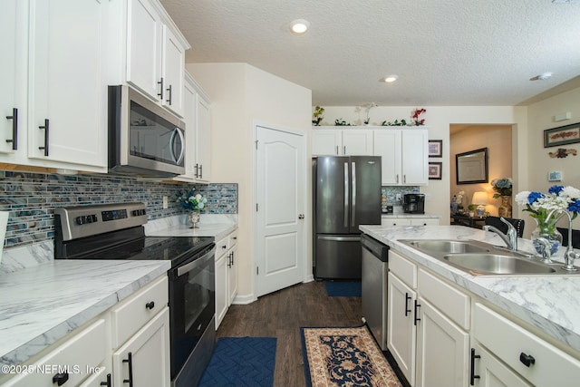 kitchen with decorative backsplash, a textured ceiling, stainless steel appliances, and white cabinets