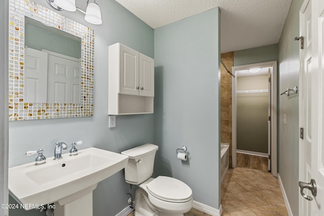 full bathroom with a textured ceiling, bathing tub / shower combination, toilet, and sink