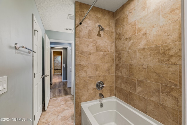 bathroom featuring tile patterned flooring, a textured ceiling, and tiled shower / bath