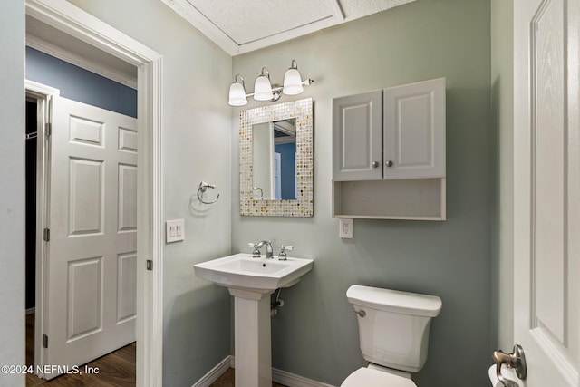 bathroom featuring sink, toilet, crown molding, and hardwood / wood-style flooring