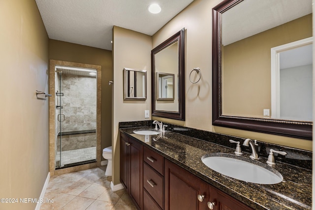 bathroom with tile patterned flooring, a textured ceiling, toilet, a shower with door, and vanity