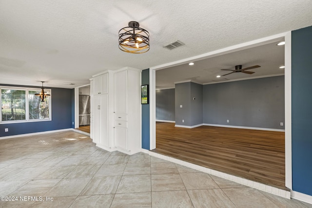 unfurnished room featuring a textured ceiling, ceiling fan with notable chandelier, and light tile patterned flooring