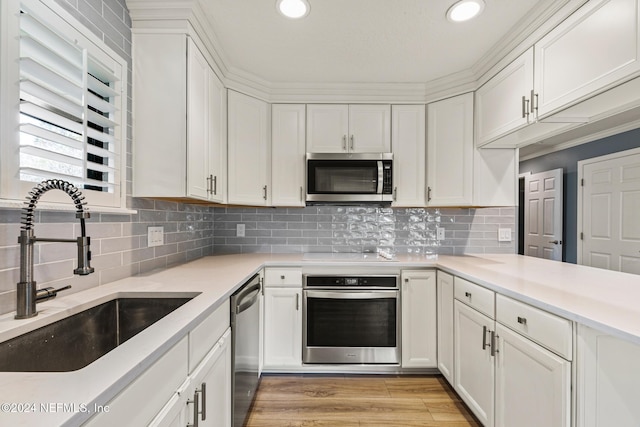 kitchen featuring white cabinets, sink, appliances with stainless steel finishes, and light hardwood / wood-style flooring