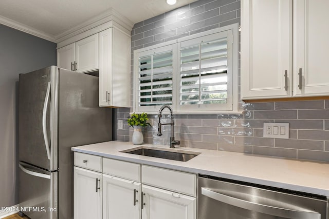 kitchen with tasteful backsplash, ornamental molding, stainless steel appliances, sink, and white cabinetry