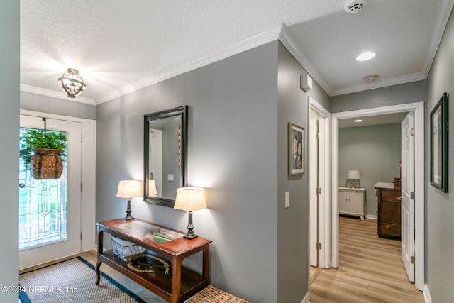 entrance foyer featuring a textured ceiling, light hardwood / wood-style flooring, and ornamental molding