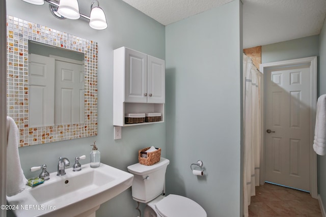 bathroom with a textured ceiling, toilet, and sink