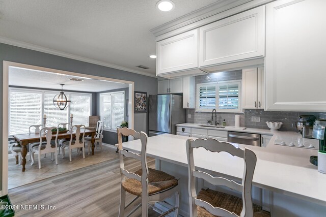 kitchen featuring white cabinetry, sink, pendant lighting, and appliances with stainless steel finishes