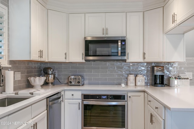 kitchen with tasteful backsplash, white cabinets, and appliances with stainless steel finishes