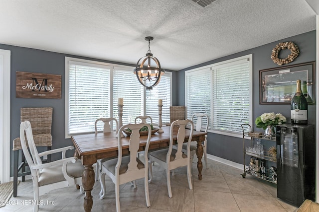 tiled dining space with a notable chandelier and a textured ceiling