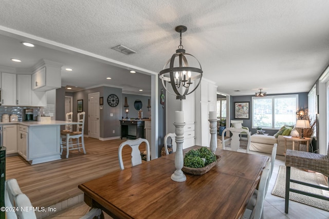 dining room featuring ceiling fan with notable chandelier, crown molding, light wood-type flooring, and a textured ceiling