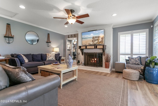 living room with hardwood / wood-style floors, crown molding, a brick fireplace, and a textured ceiling