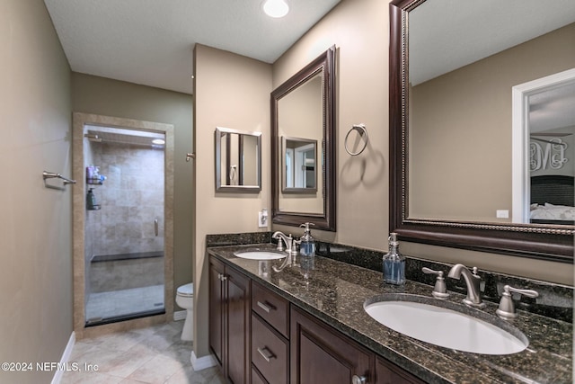 bathroom featuring a tile shower, tile patterned flooring, vanity, and toilet