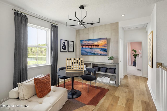 living room featuring a chandelier, light hardwood / wood-style floors, and a textured ceiling